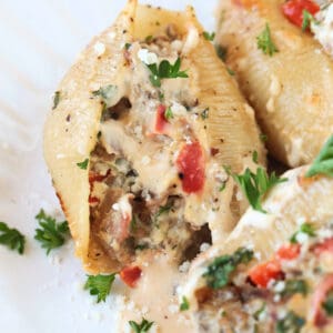 stuffed shells with shaved beef and pepper filling on white plate