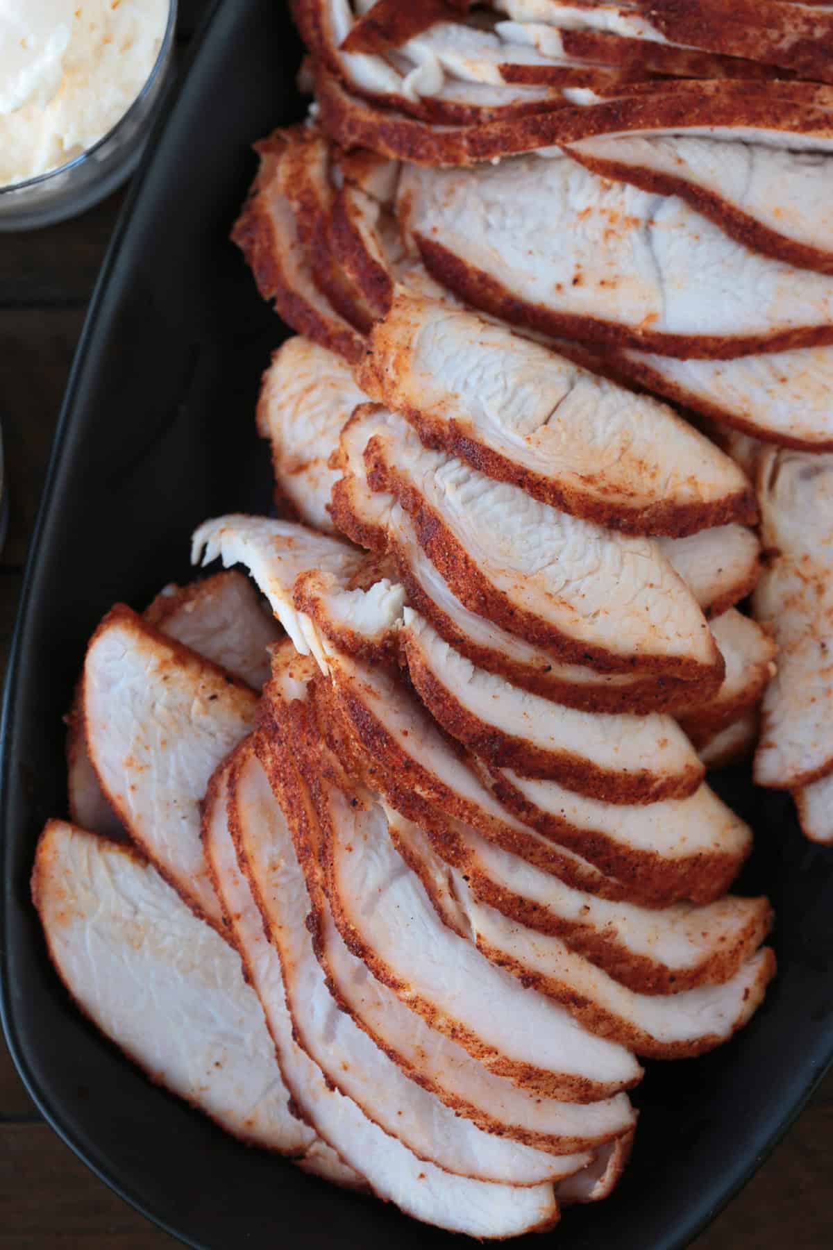 Skip the deli and make our Homemade Turkey Deli Meat instead! Not only is it super flavorful, it's less expensive and better for you, too! close up of sliced turkey on black platter