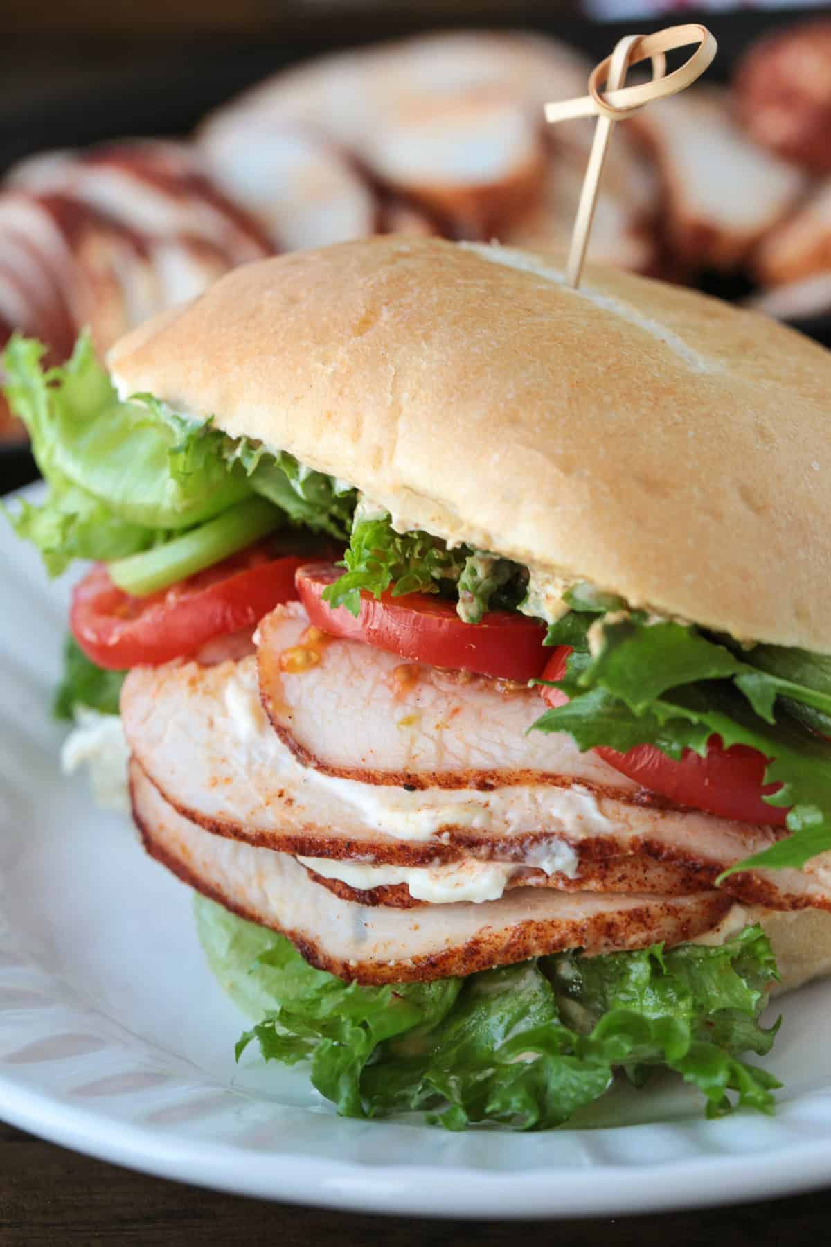 Skip the deli and make our Homemade Turkey Deli Meat instead! Not only is it super flavorful, it's less expensive and better for you, too! turkey sandwich on plate with sliced turkey in the background