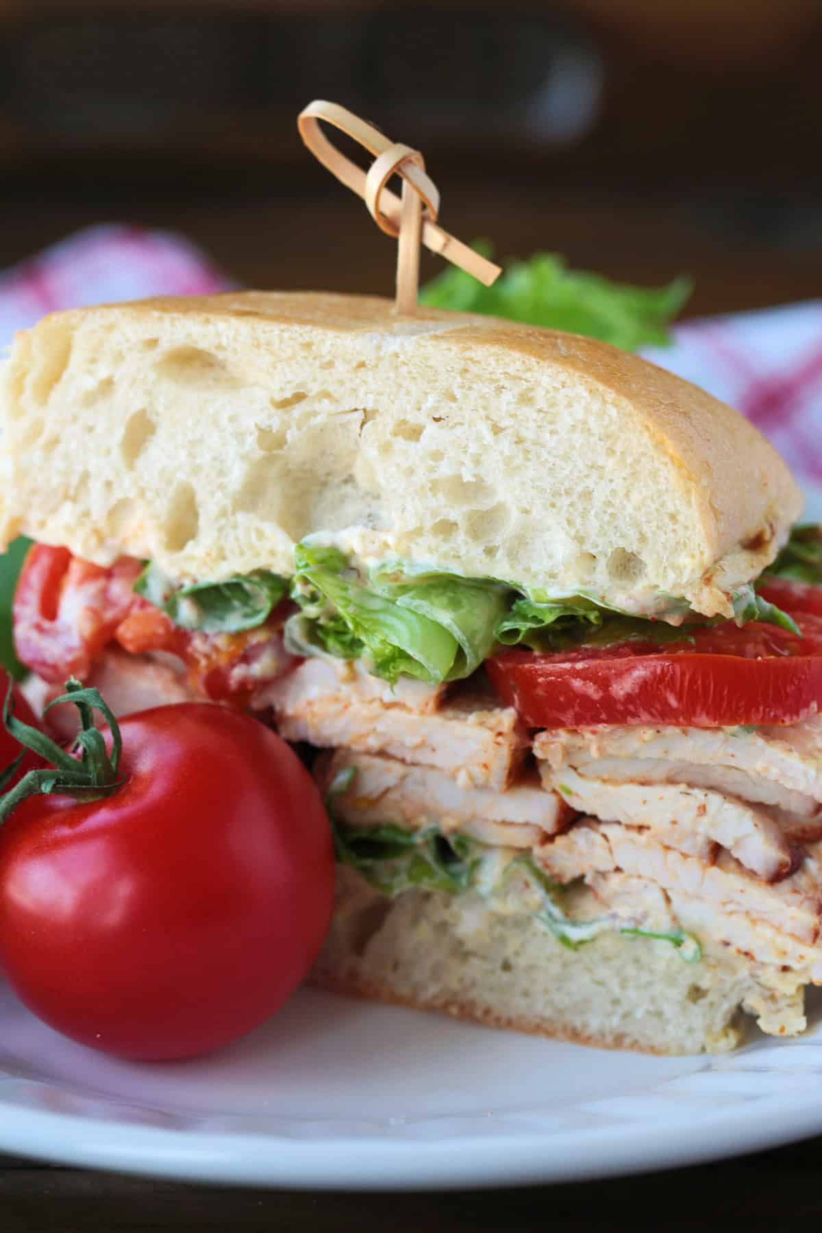Skip the deli and make our Homemade Turkey Deli Meat instead! Not only is it super flavorful, it's less expensive and better for you, too! turkey sandwich cut in half on plate with tomatoes