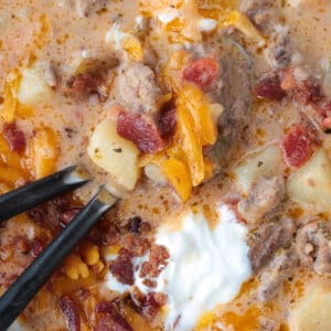 cheeseburger soup in a bowl with two spoons