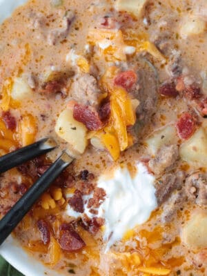cheeseburger soup in a bowl with two spoons