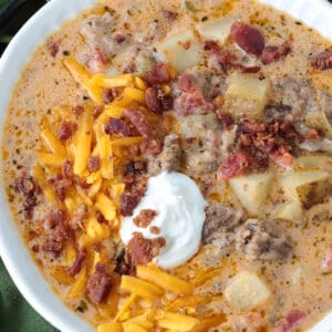 cheeseburger soup in a bowl topped with sour cream, cheese and bacon