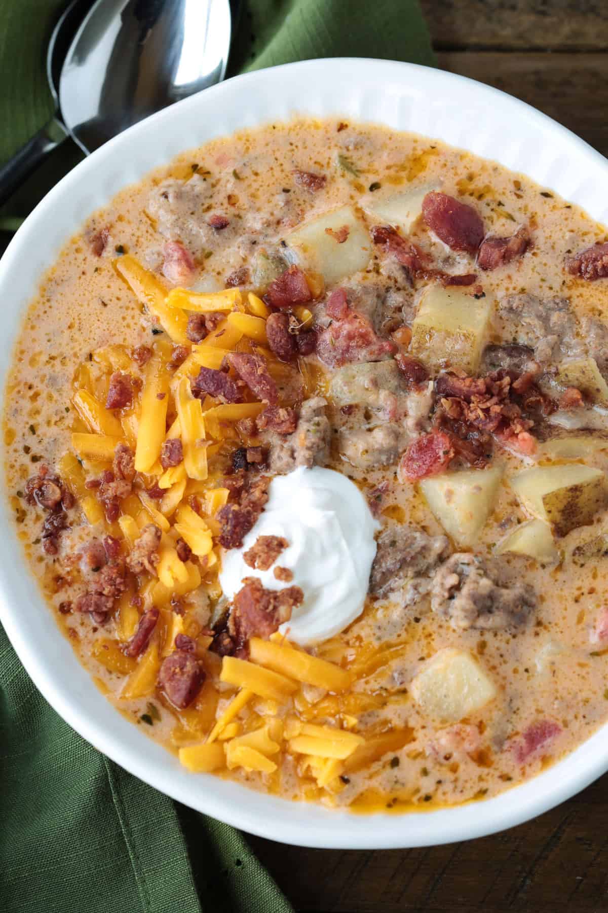 Rich and creamy cheeseburger soup is packed with ground beef, real cheddar cheese and potatoes for the ultimate cozy comfort food dinner. cheeseburger soup in a bowl topped with sour cream, cheese and bacon