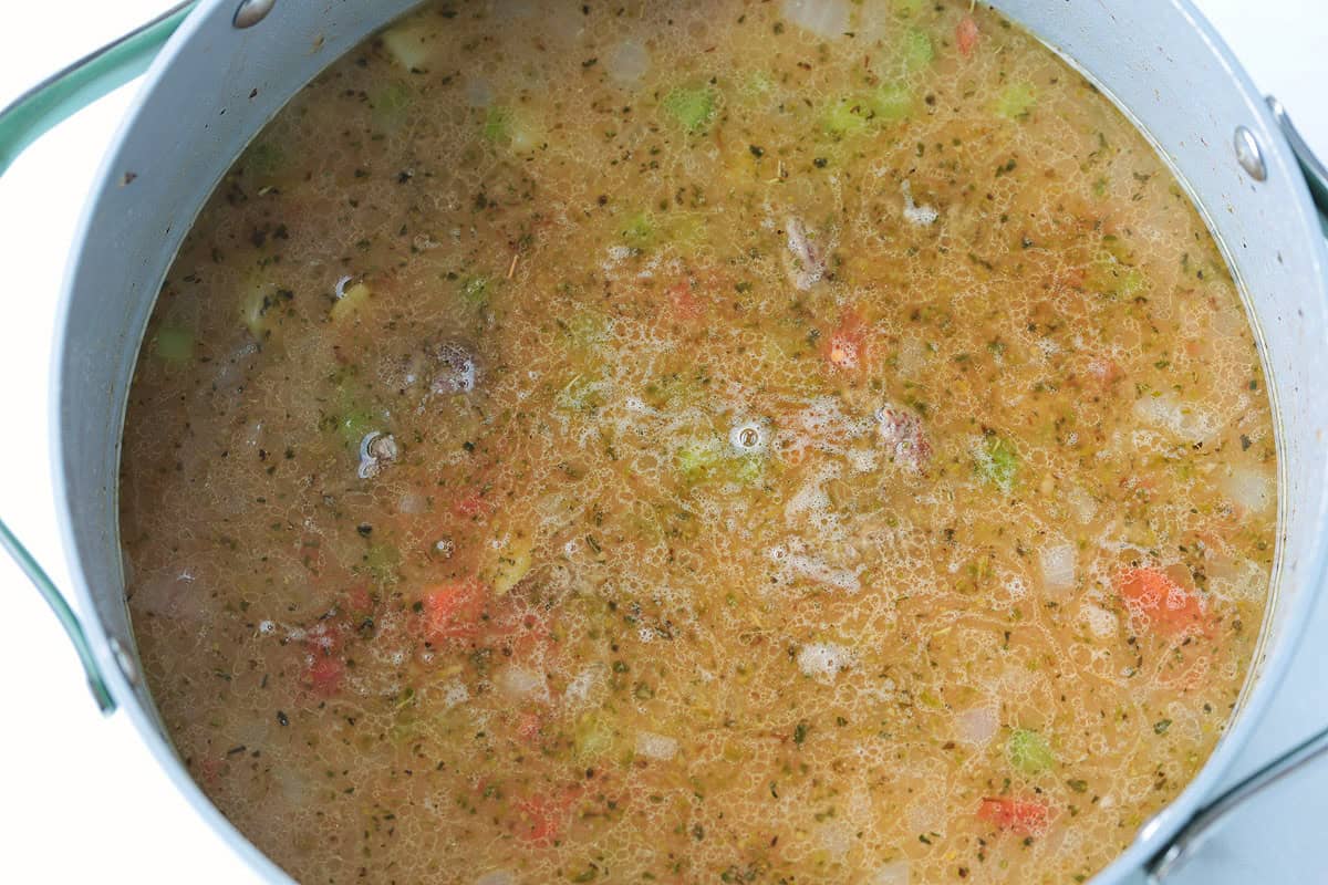 Rich and creamy cheeseburger soup is packed with ground beef, real cheddar cheese and potatoes for the ultimate cozy comfort food dinner. broth in a soup pot with ground beef and potatoes