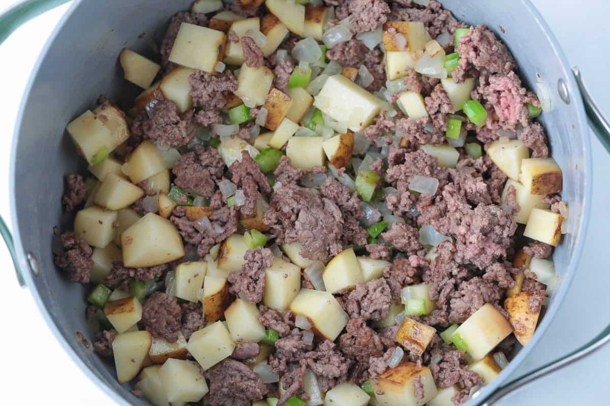 Rich and creamy cheeseburger soup is packed with ground beef, real cheddar cheese and potatoes for the ultimate cozy comfort food dinner. ground beef and potatoes in a soup pot