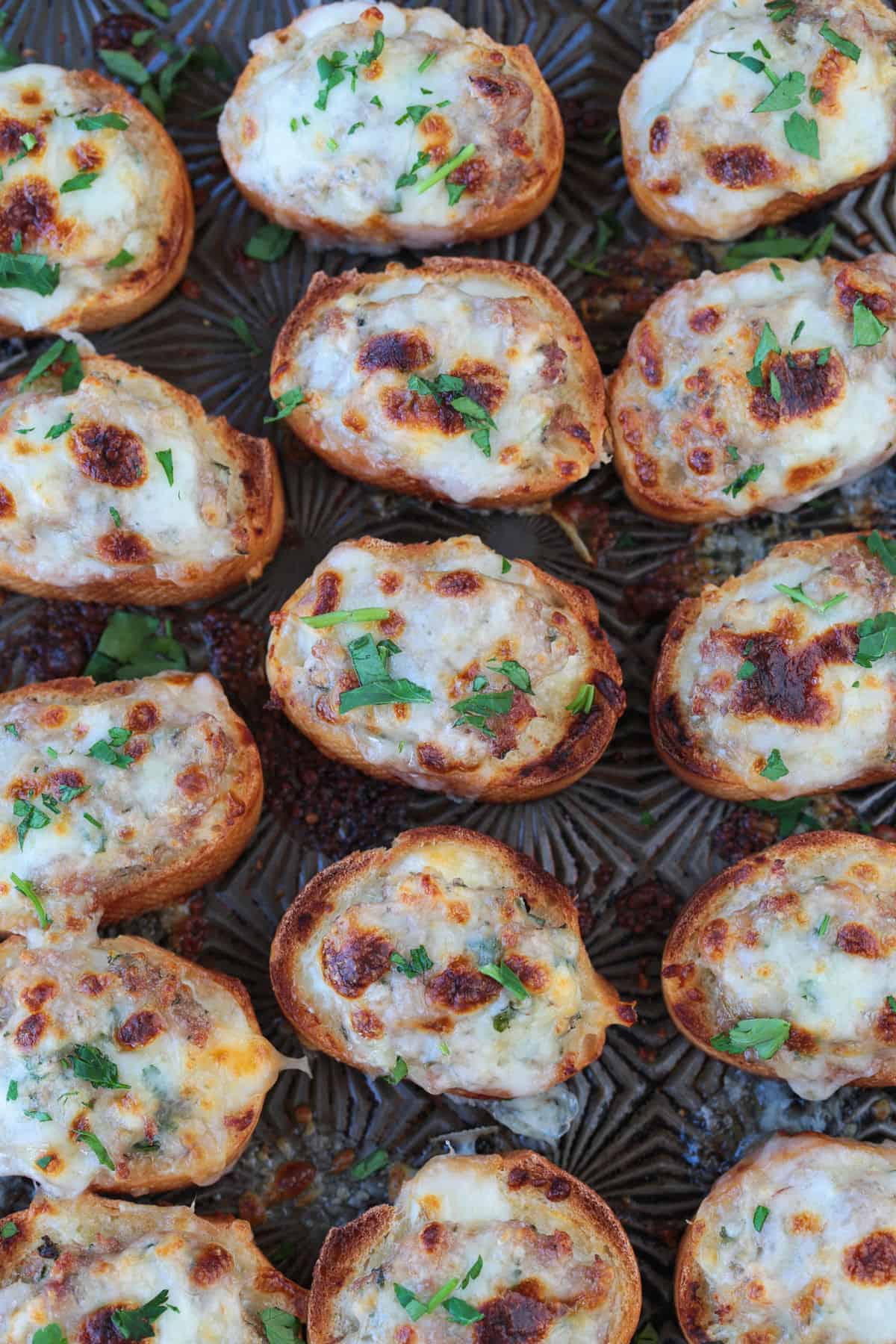 baking sheet with sausage crostini topped with cheese and broiled