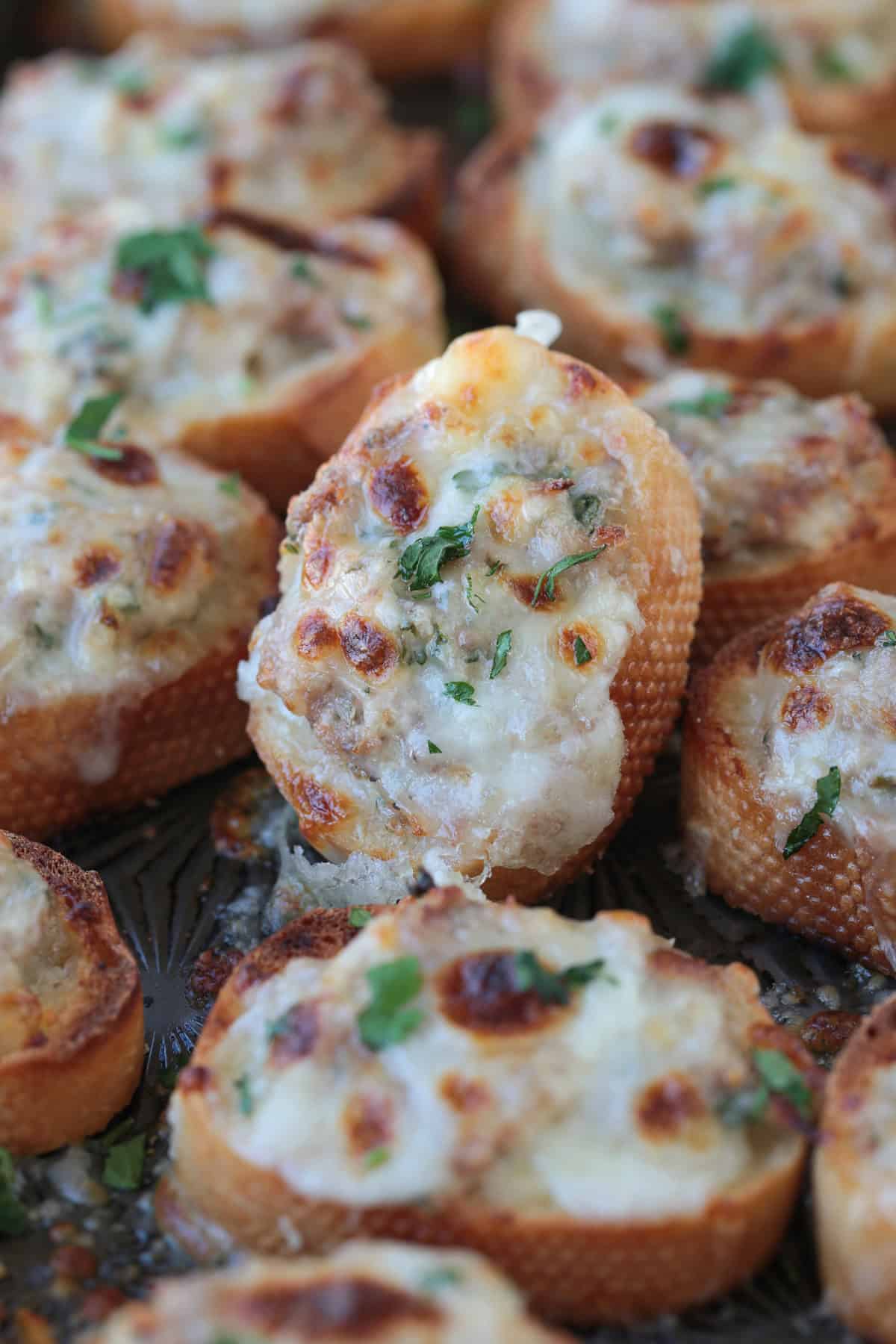 crostini with cheese propped up on a tray of baked crostini