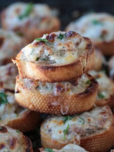 cheesy sausage crostini stacked on a tray of crostini