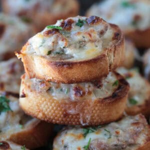 cheesy sausage crostini stacked on a tray of crostini