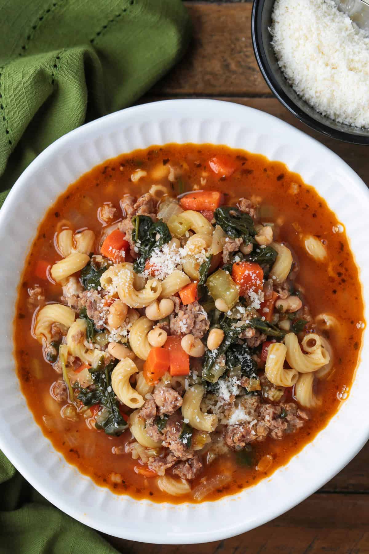 minestrone soup with sausage in white bowl with parmesan cheese
