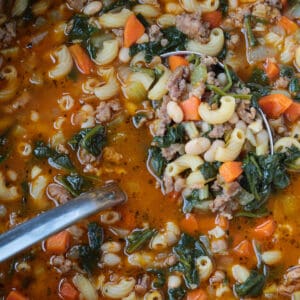 sausage minestrone soup in a pot with ladle