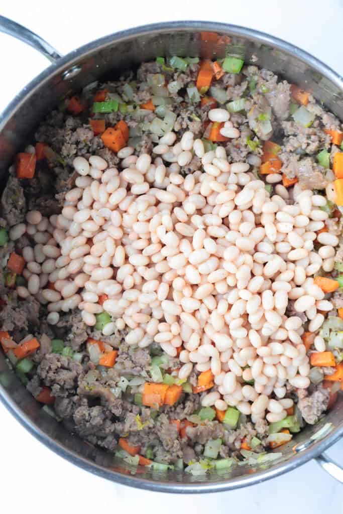 white beans in a pot with sausage and vegetables