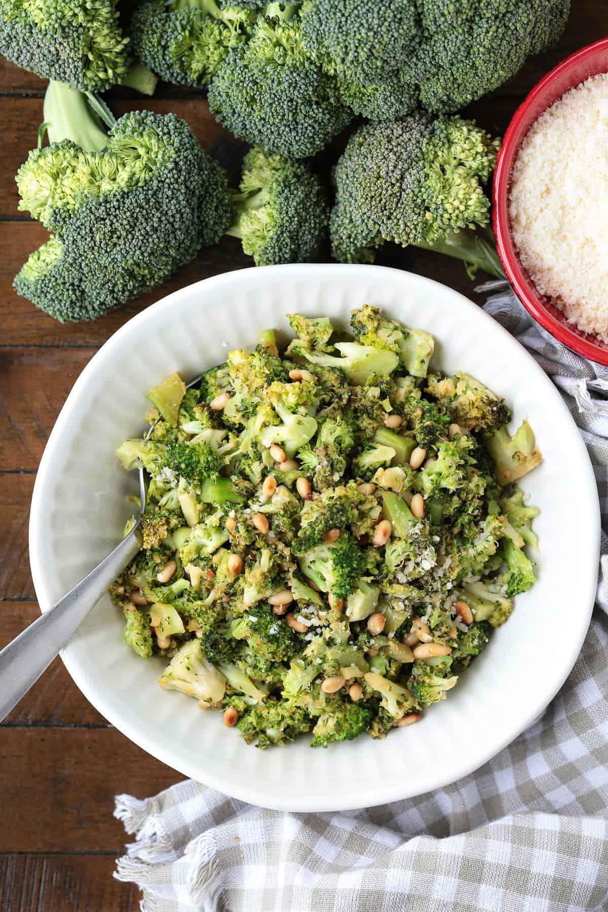 shaved broccoli in a white bowl with pignoli nuts and parmesan cheese
