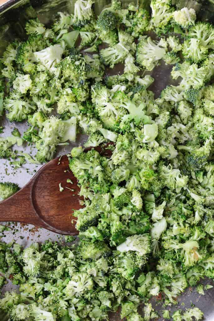 chopped broccoli in a skillet with wooden spoon