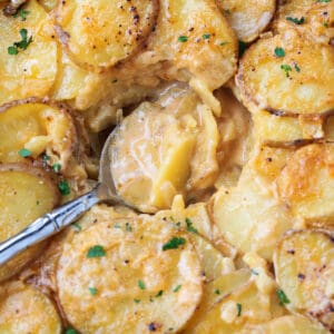 cheesy potato casserole in serving dish with spoon