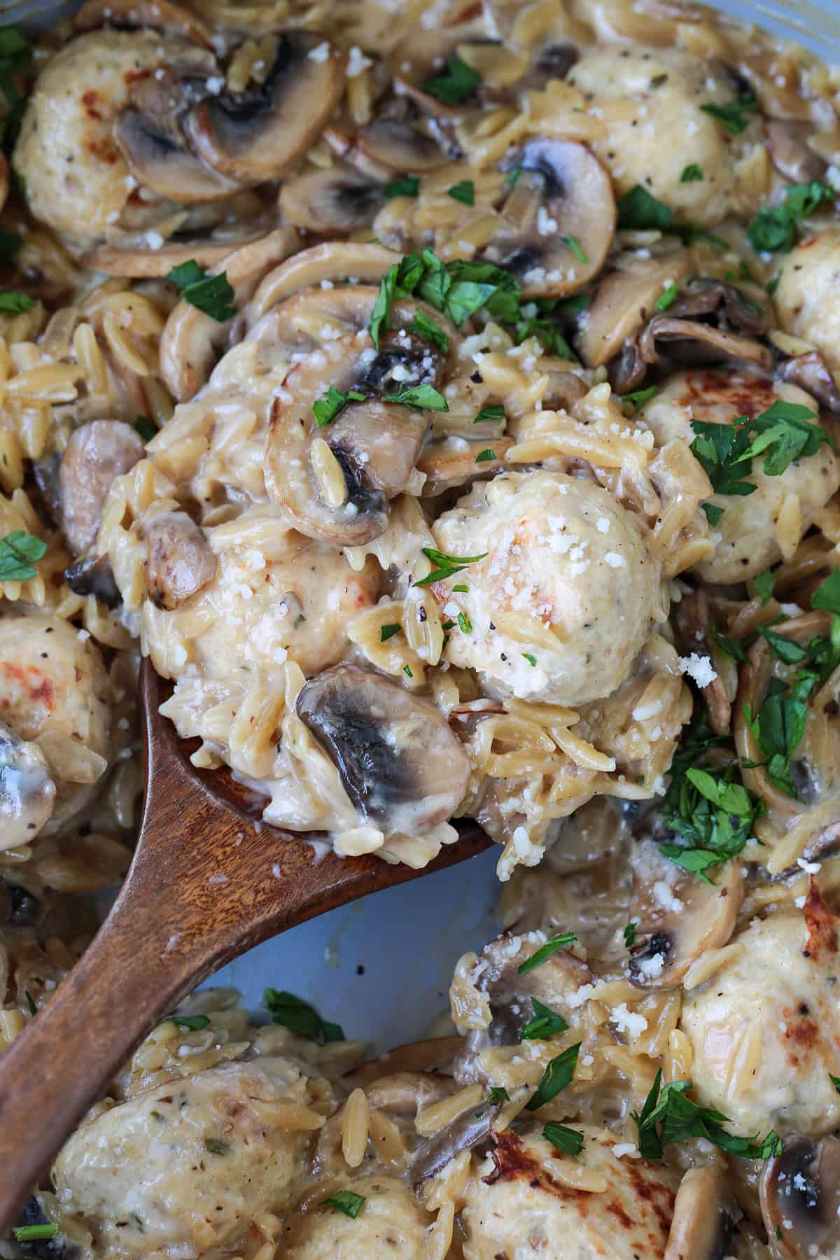 spoon in skillet with chicken meatballs and mushroom orzo