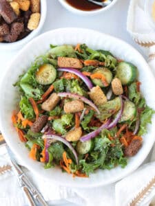 salad in a white bowl with croutons on the side