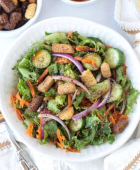 salad in a white bowl with croutons on the side