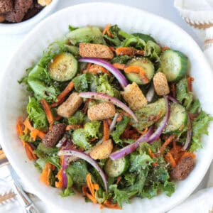 salad in a white bowl with croutons on the side