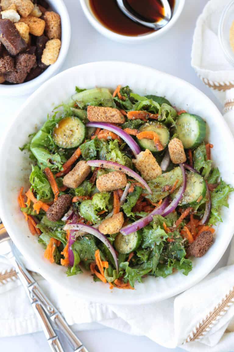 salad in a white bowl with croutons on the side