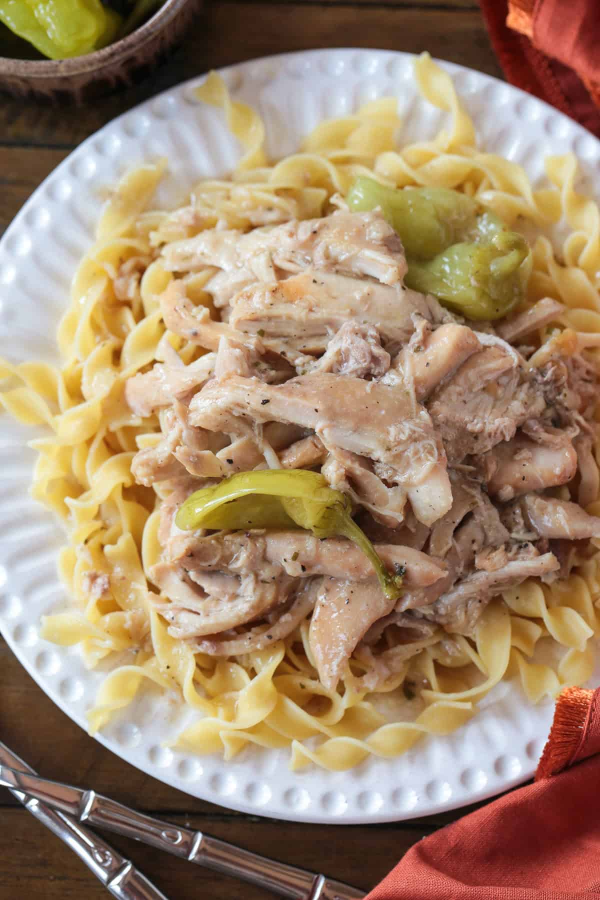 Mississippi Chicken is an easy, 5 ingredient dinner! Tender chicken in a tangy and zesty gravy spooned over mashed potatoes or noodles! mississippi chicken on a plate with noodles