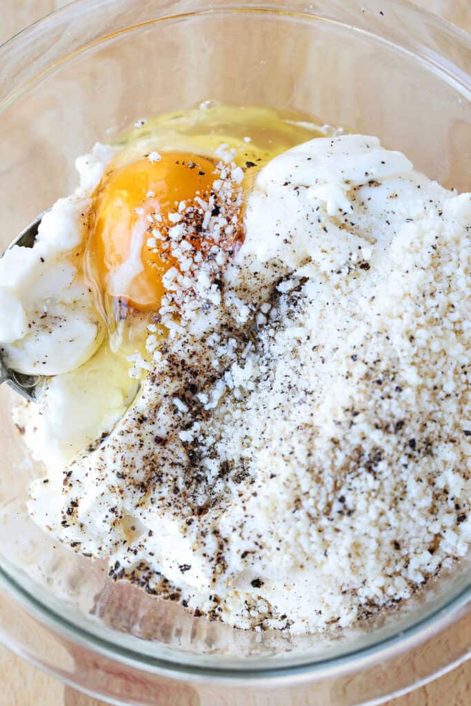 egg in a bowl with ricotta and parmesan cheese and seasonings