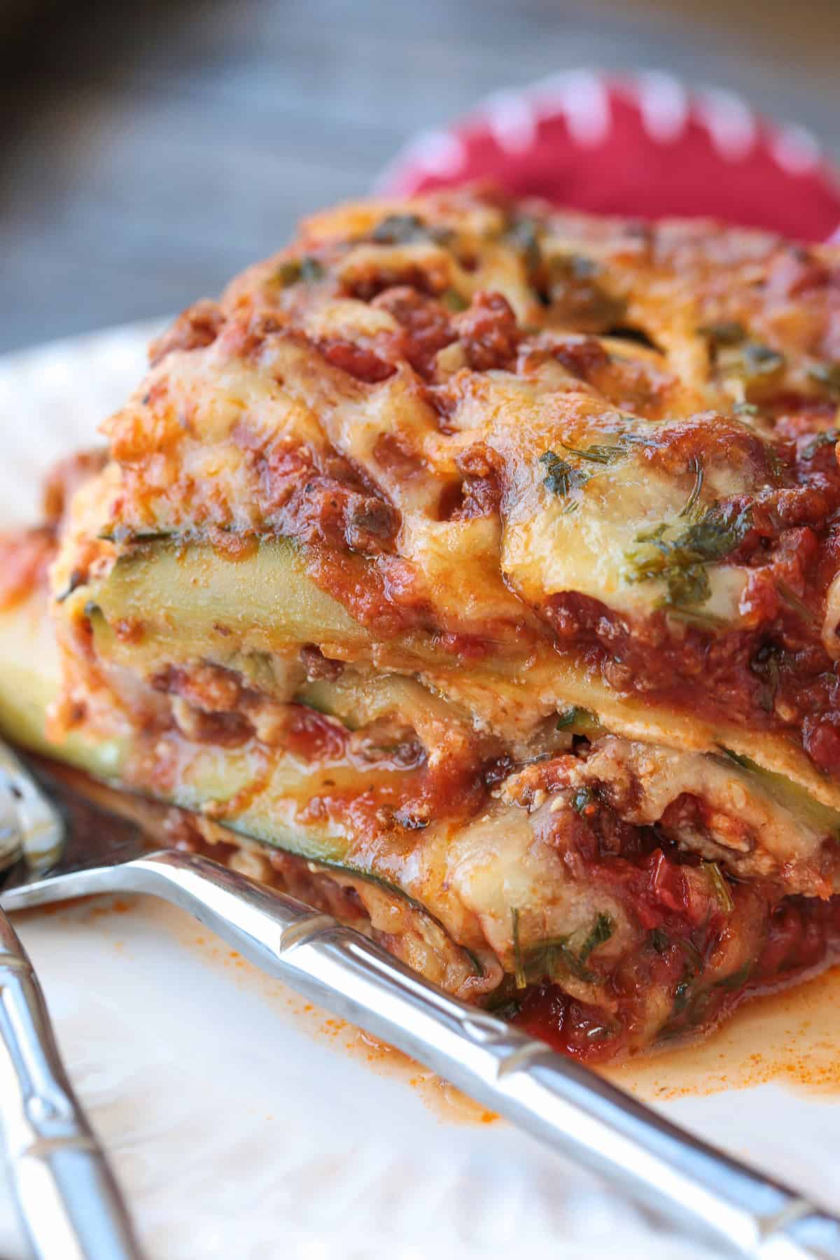 Our Fool Proof Zucchini Lasagna turns out perfect every time. Thin strips of zucchini make a lighter lasagna recipe with tons of flavor! slice of zucchini lasagna on white plate with fork