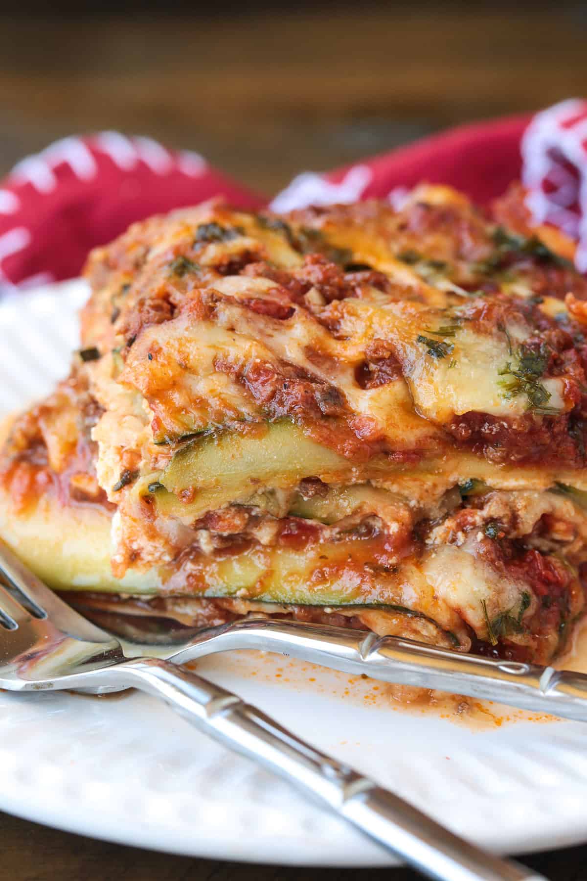 Our Fool Proof Zucchini Lasagna turns out perfect every time. Thin strips of zucchini make a lighter lasagna recipe with tons of flavor! slice of zucchini lasagna on a plate with fork