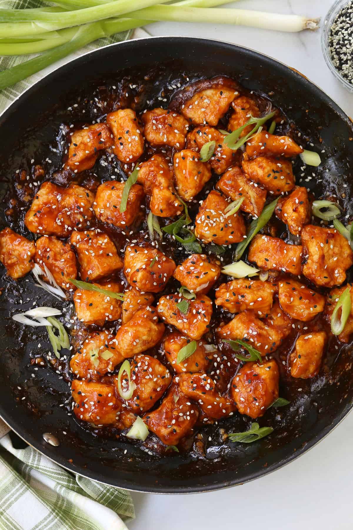 Air Fryer General Tso's Chicken is a lighter take on the take-out recipe that you'll love. The same flavors you crave but without the oil. skillet with general tso's chicken garnished with sesame seeds