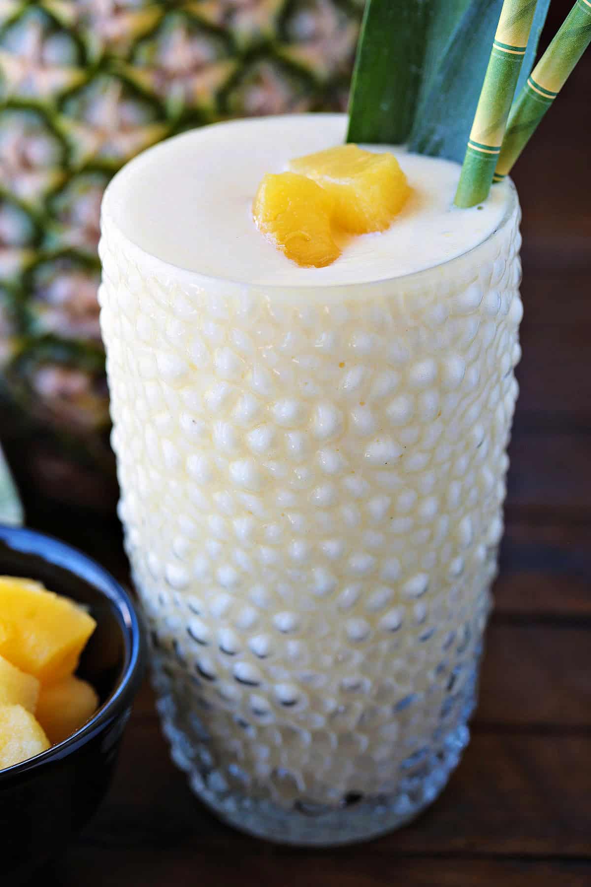 pineapple smoothie in glass with pineapple in background