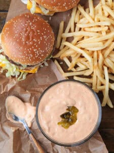 big mac and fries on a board with sauce in a bowl