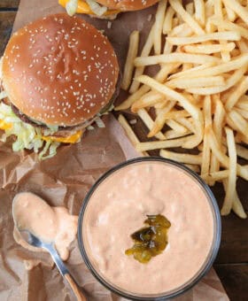 big mac and fries on a board with sauce in a bowl