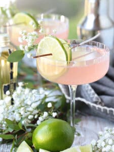 cosmopolitan cocktail with limes and floral garnish