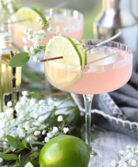 cosmopolitan cocktail with limes and floral garnish