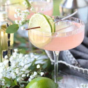 cosmopolitan cocktail with limes and floral garnish