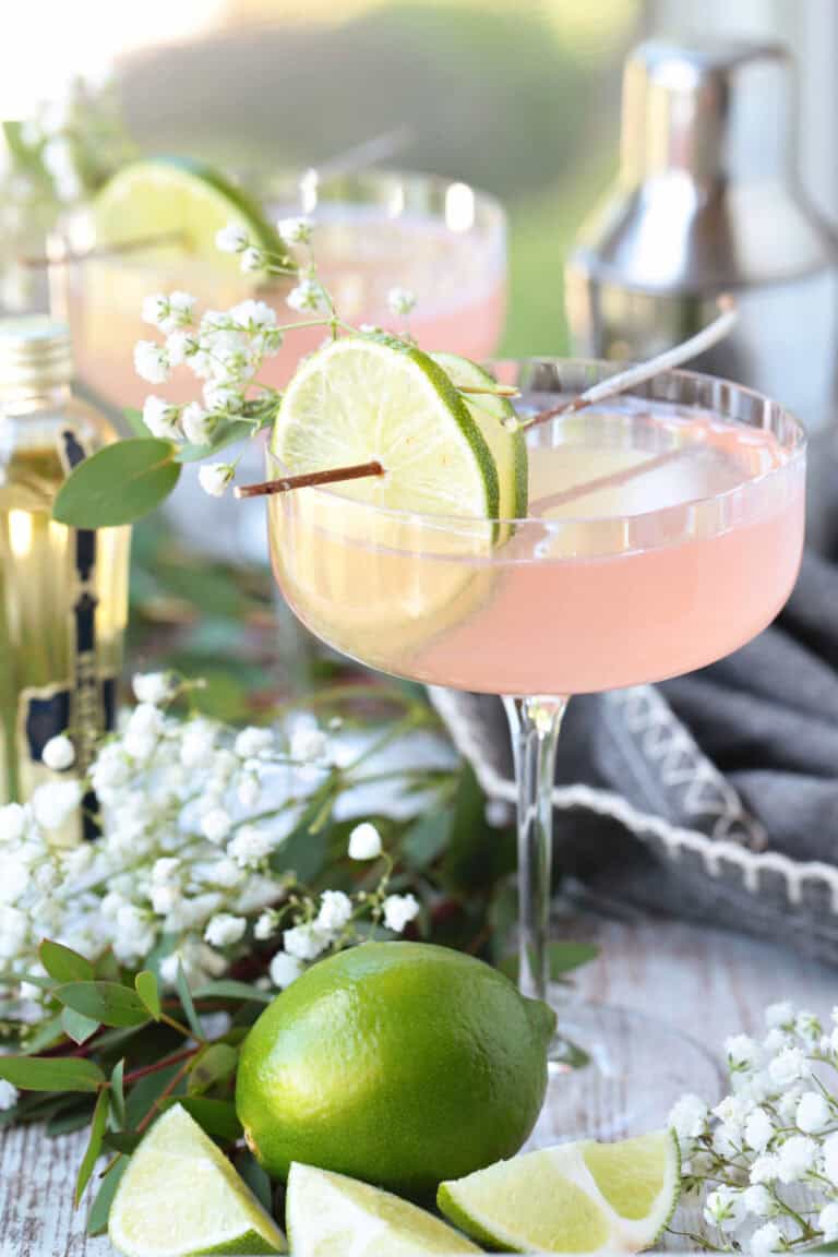 cosmopolitan cocktail with limes and floral garnish