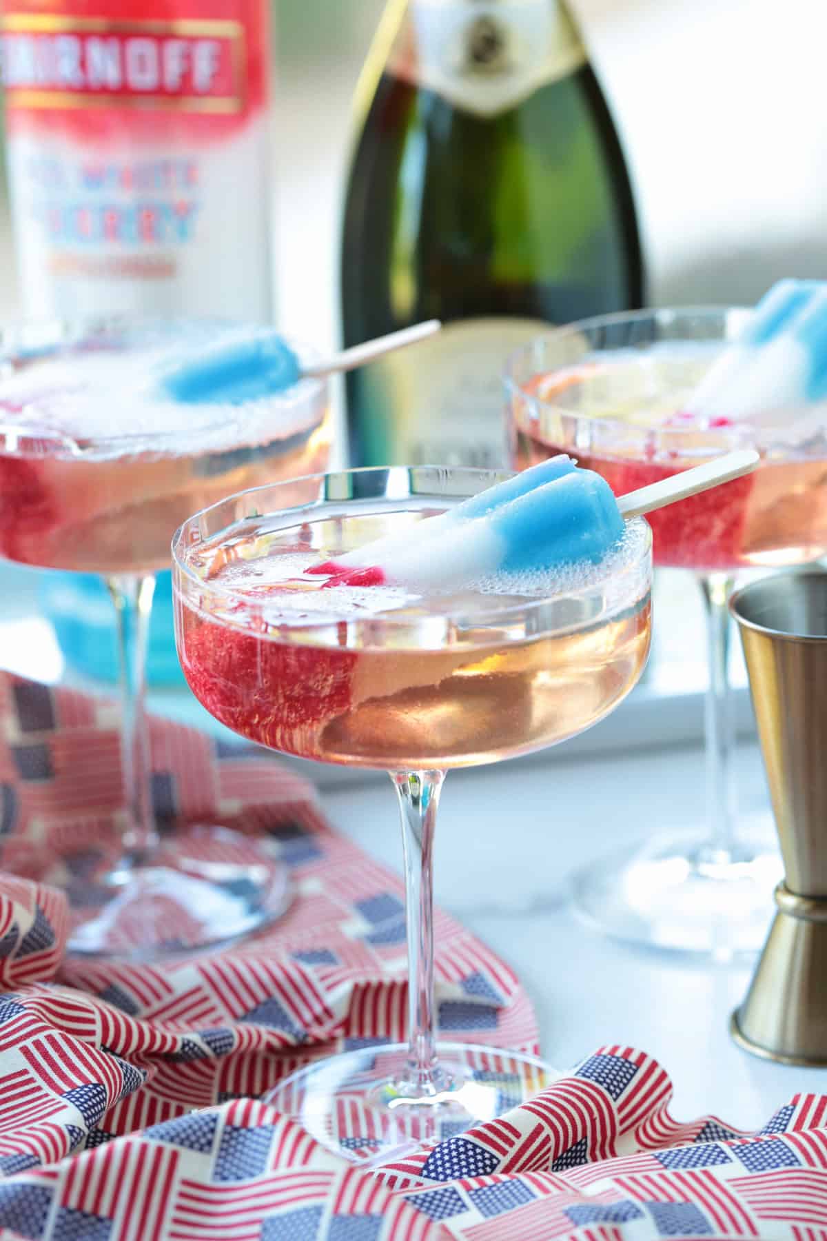 This Bomb Pop Cocktail is the easiest summer drink you'll ever make! The popsicle melts into the champagne for added fun and flavor! champagne cocktails with bomb pops as garnish