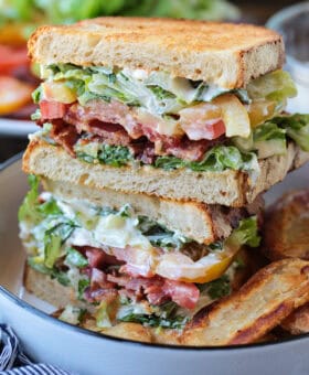 blt sandwich sliced and stacked on a plate with chips