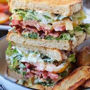 blt sandwich sliced and stacked on a plate with chips