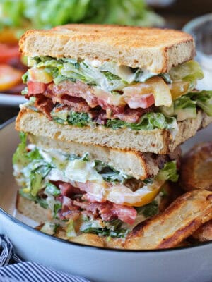blt sandwich sliced and stacked on a plate with chips