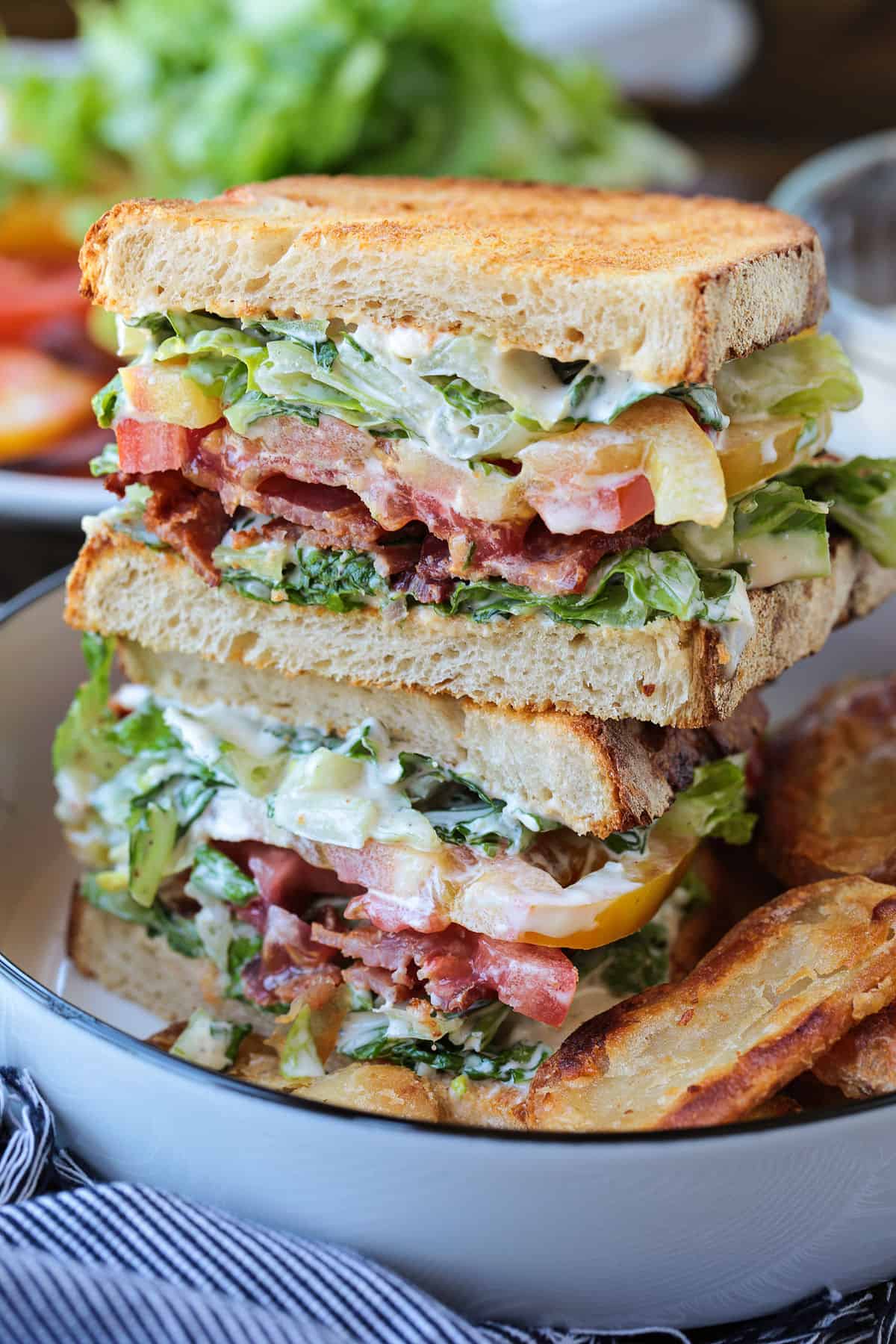 blt sandwich sliced and stacked on a plate with chips