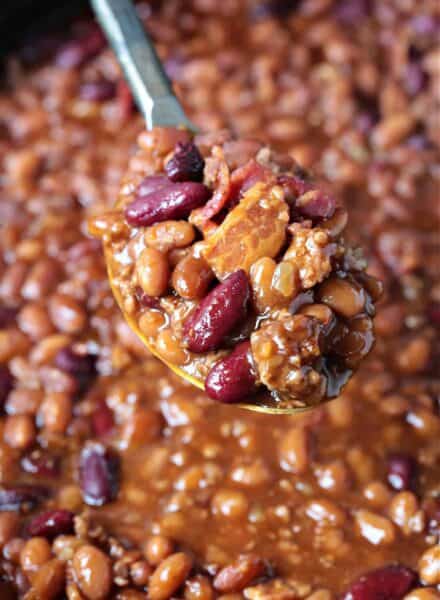 baked beans with bacon and ground beef on serving spoon