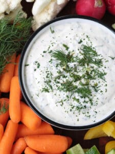 close up of ranch dip in a bowl with vegetables on the side