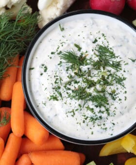 close up of ranch dip in a bowl with vegetables on the side