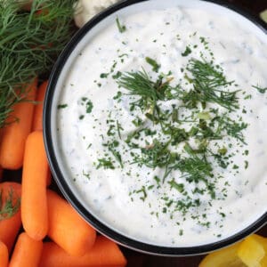 close up of ranch dip in a bowl with vegetables on the side