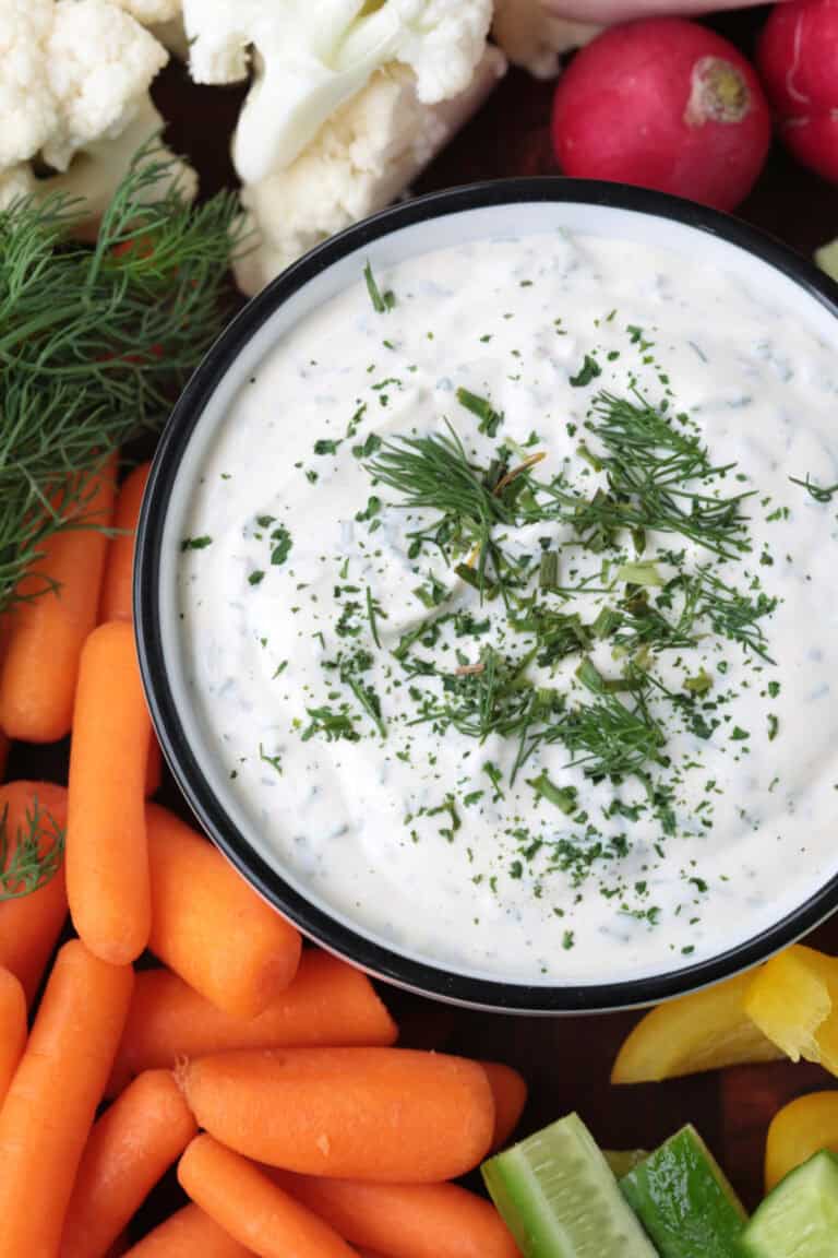 close up of ranch dip in a bowl with vegetables on the side