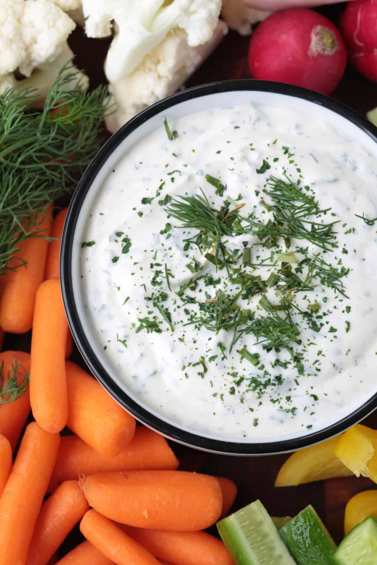 One taste of our Homemade Ranch Dip and you won't go back to store bought! Just five minutes to make – it's fresh and herby and so addicting. close up of ranch dip in a bowl with vegetables on the side