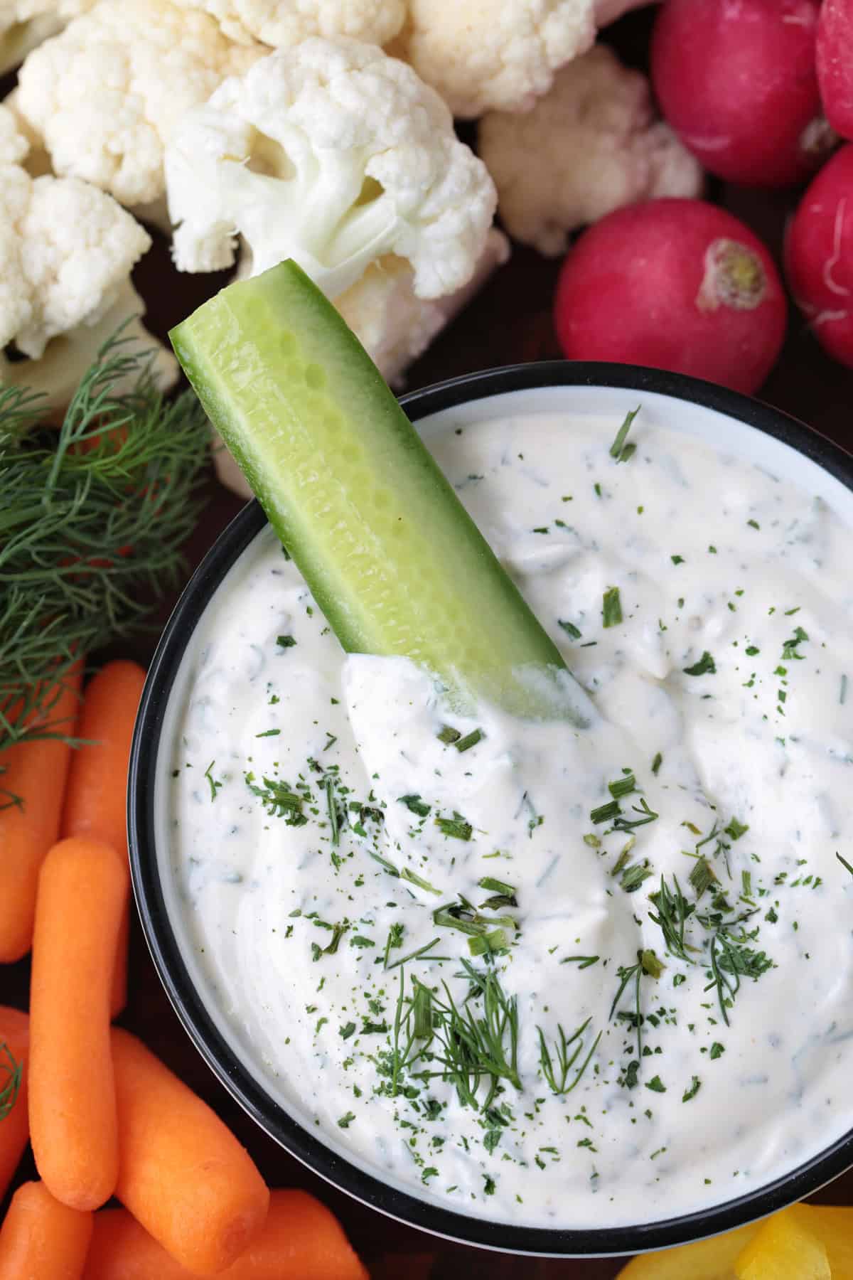 One taste of our Homemade Ranch Dip and you won't go back to store bought! Just five minutes to make – it's fresh and herby and so addicting. cucumber dipping into a bowl of ranch