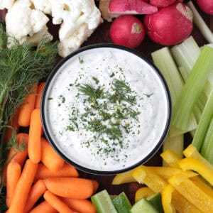board with homemade ranch in a bowl surrounded with vegetables